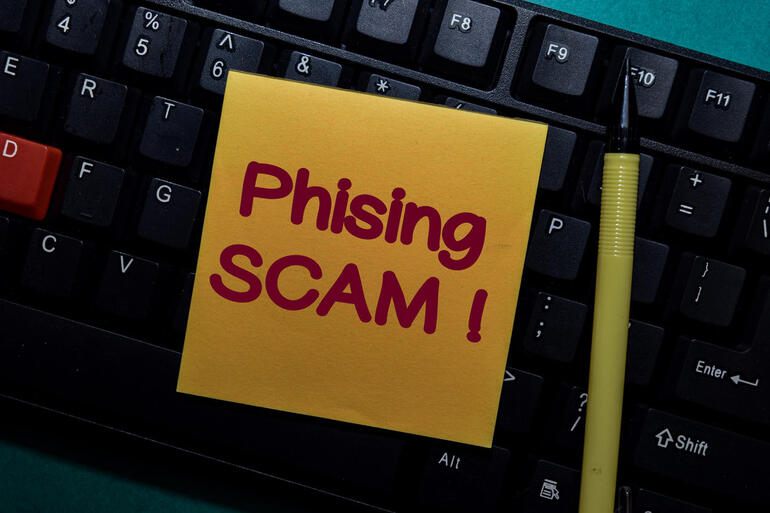 Phising Scam! write on a sticky note isolated on Office Desk