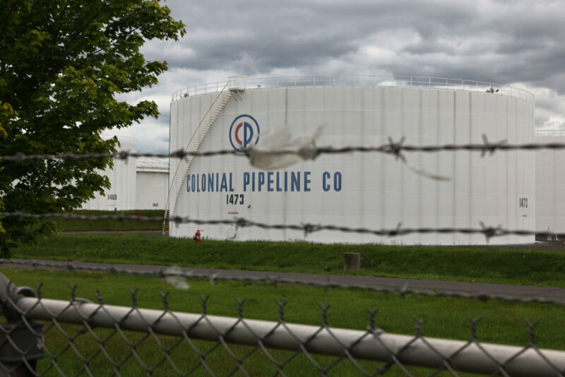 A chainlink fence separates us from fossil fuel tanks.