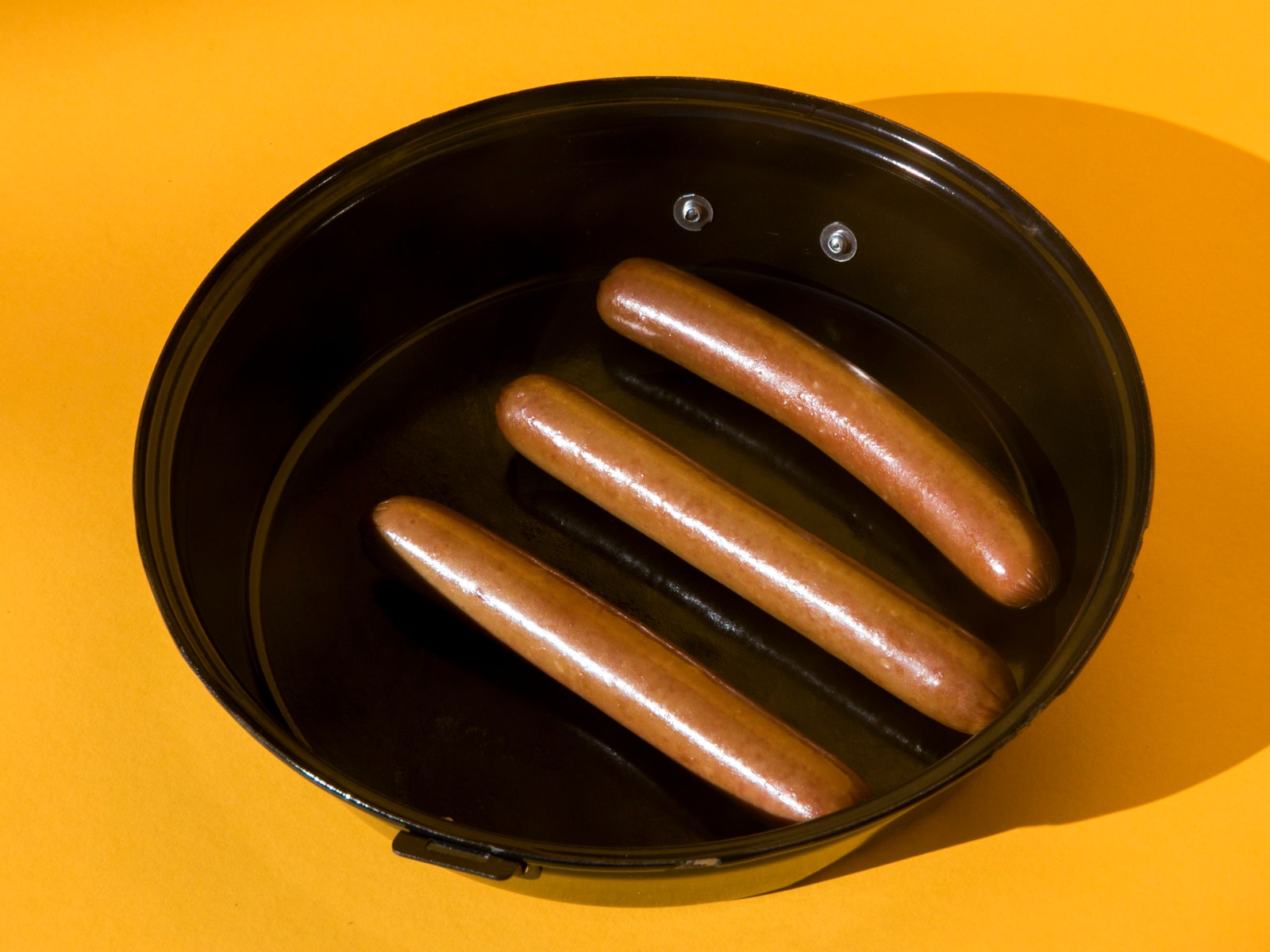 three hot dogs in a black pan