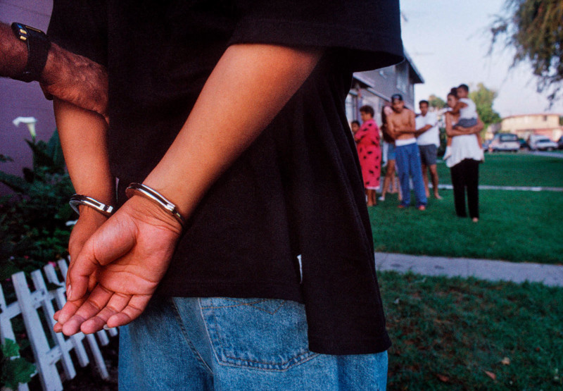 Murder suspect is arrested as his family watches.