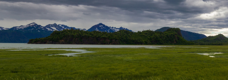 An Alaskan landscape with mountains, grassland, and water